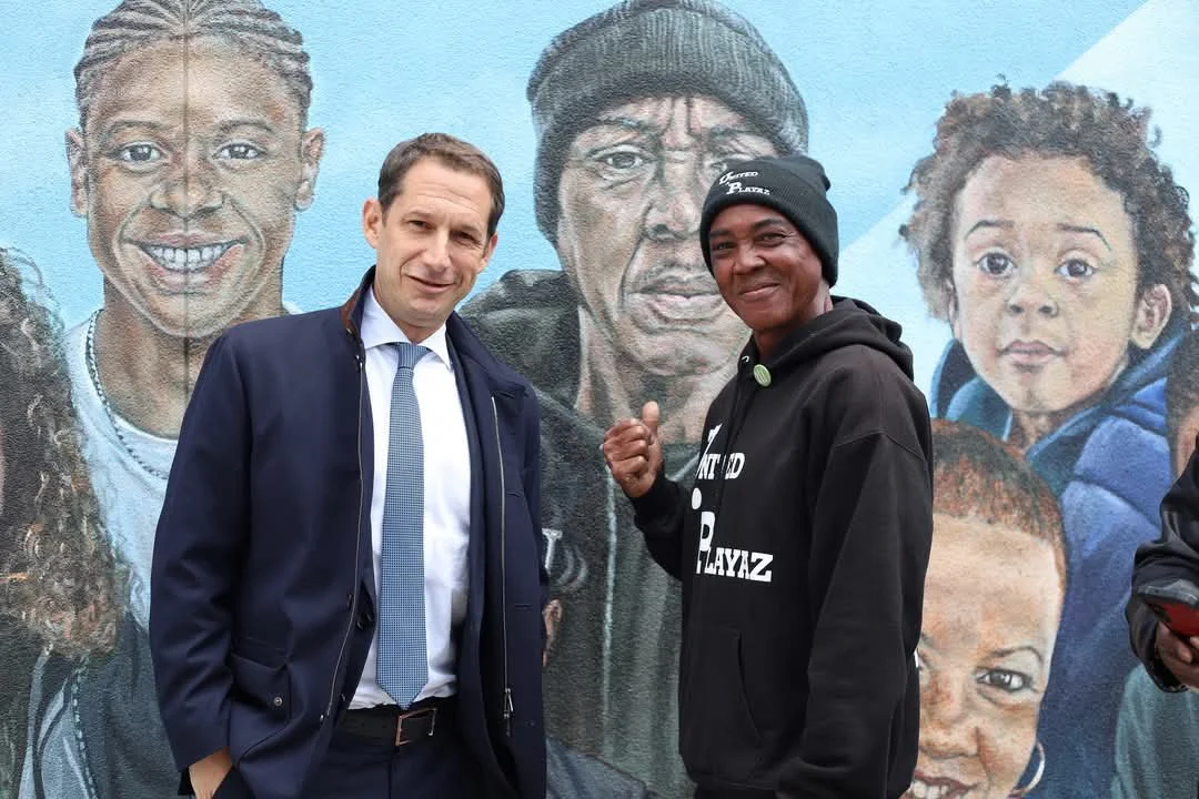 Oscar Grant Jr. with a community partner in front of a mural honoring Oakland residents