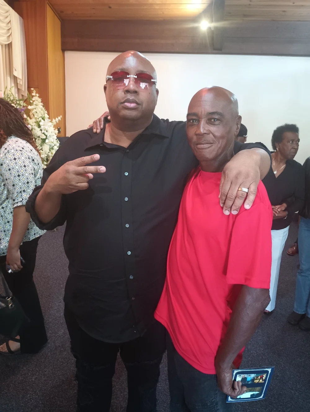 Oscar Grant Jr. standing with a community member at an indoor gathering
